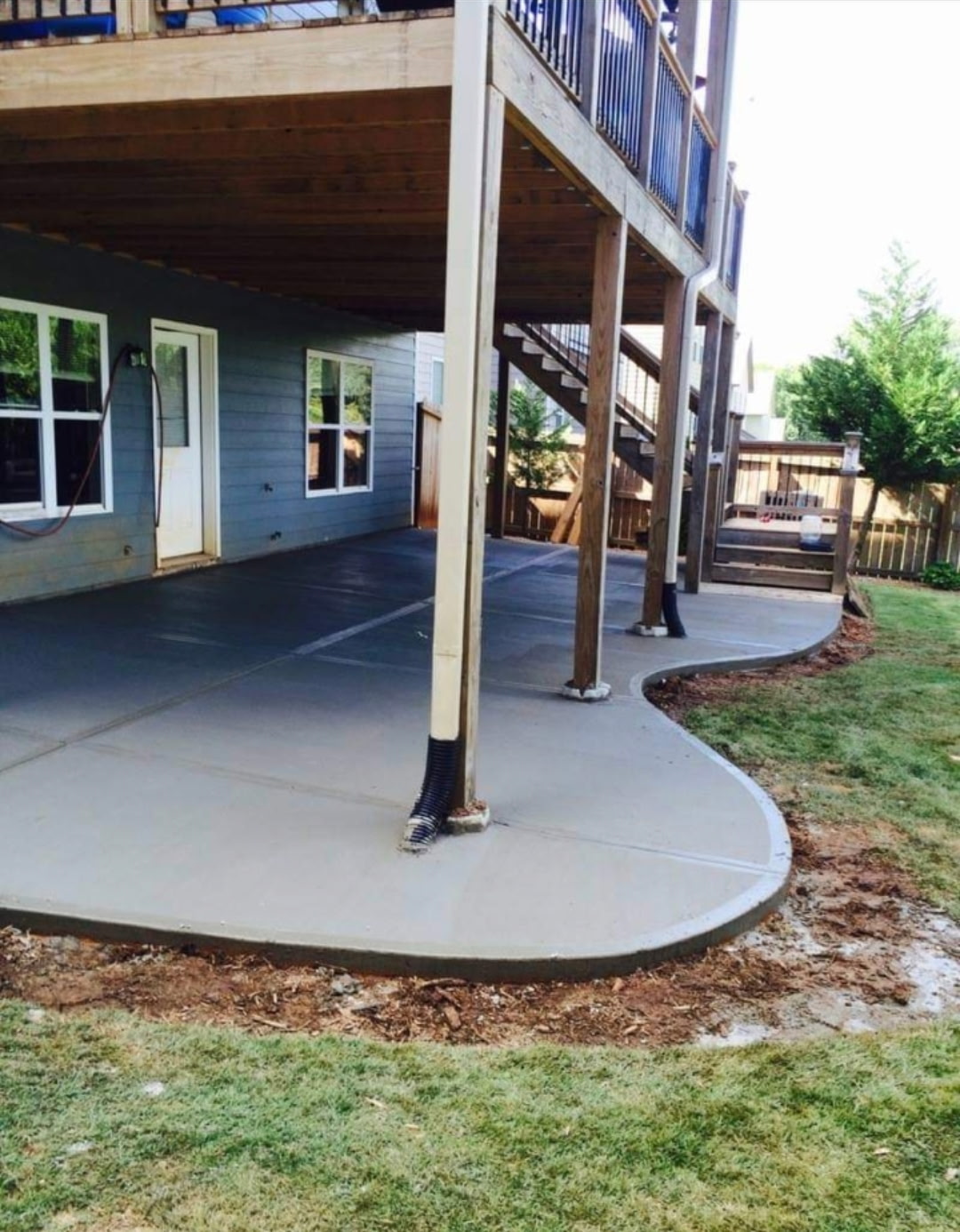 Curved concrete patio poured beneath an elevated deck