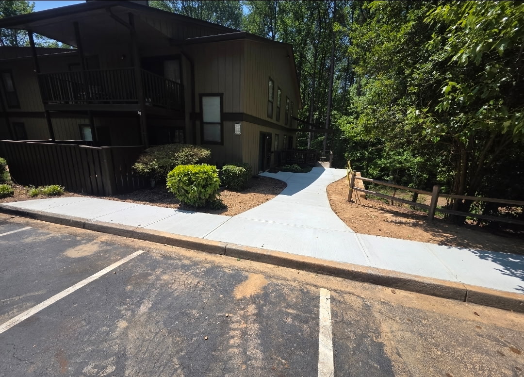 Newly poured curving concrete sidewalk leading to an apartment building