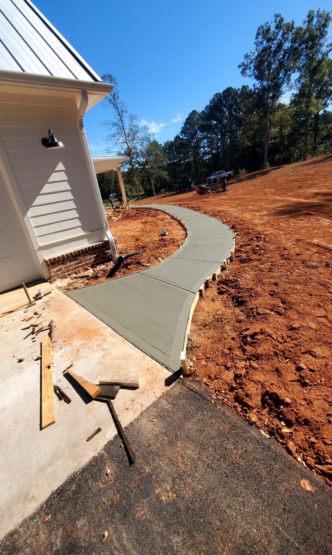 Curved concrete walkway alongside a white farmhouse