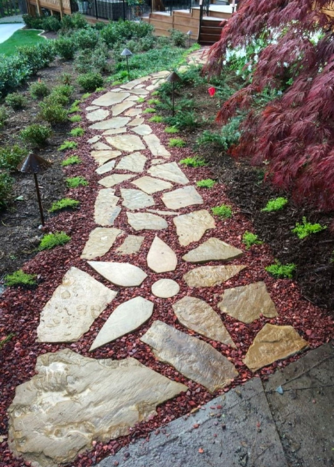 Flagstone path set in red lava rock with a mosaic flower medallion inlay