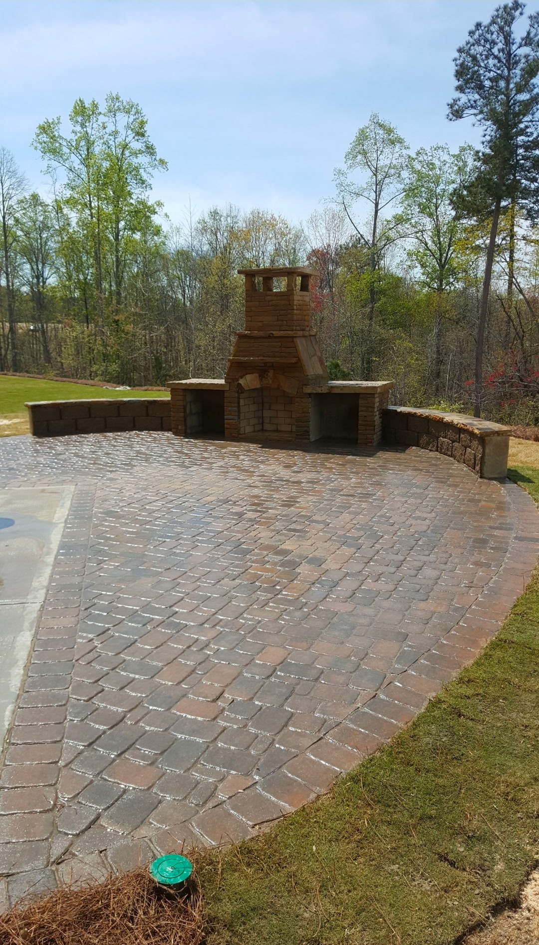 Curved paver patio with a stacked-stone seating wall and outdoor fireplace