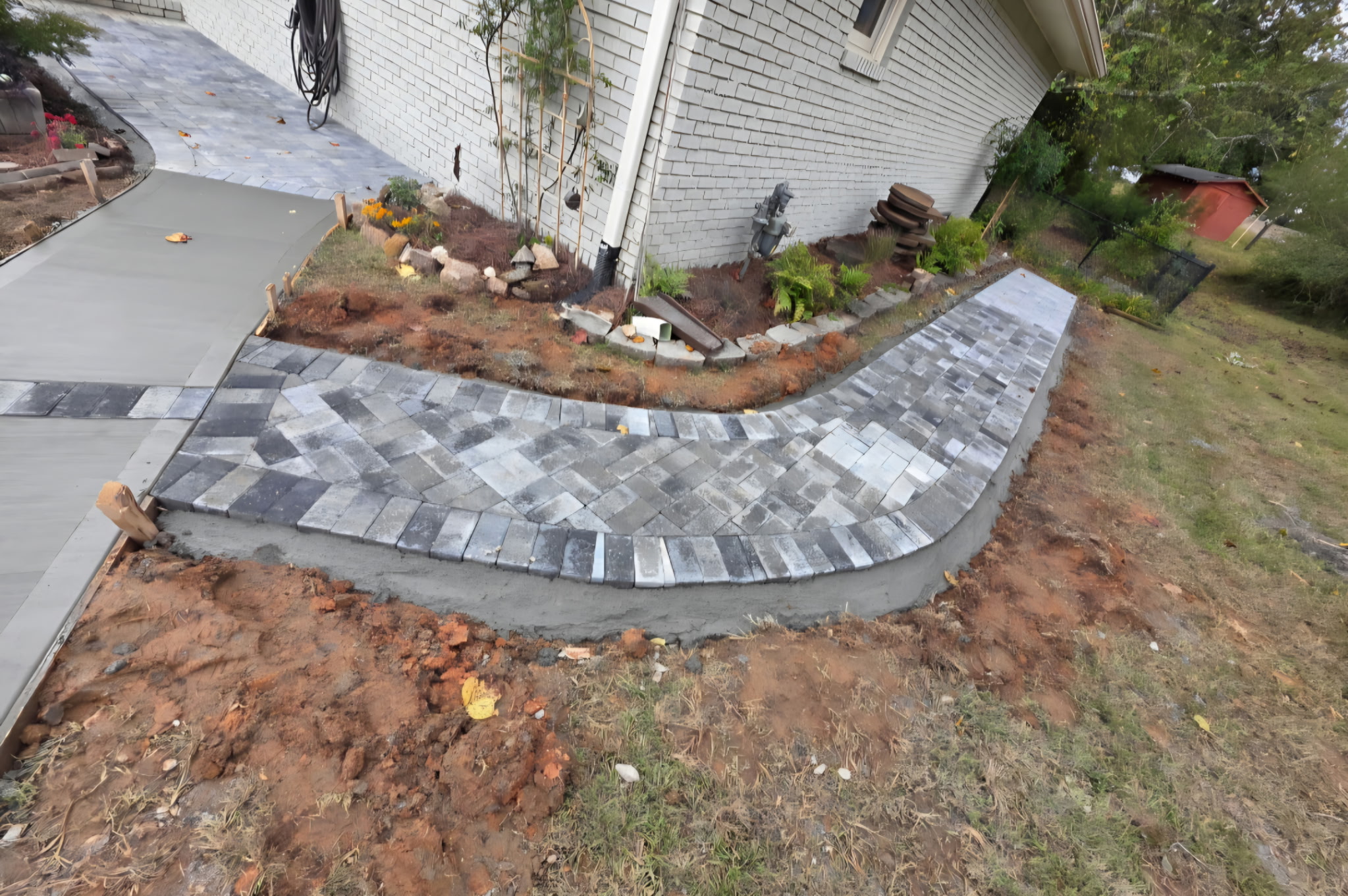Curved charcoal paver walkway with a soldier-course border alongside a driveway