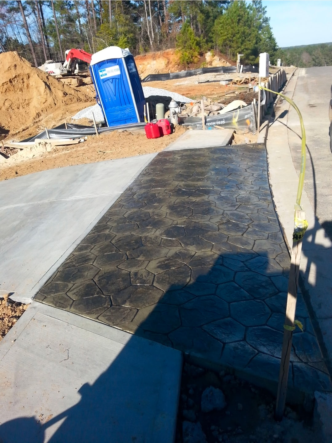 Stamped-concrete driveway skirt with a dark hexagonal cobblestone pattern