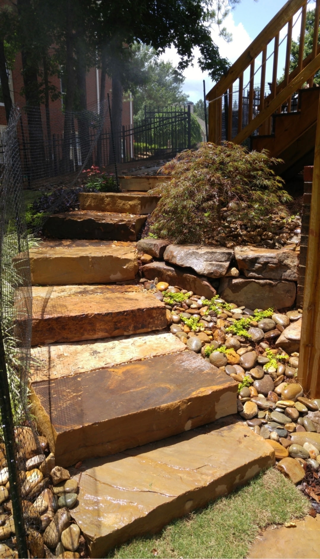 Natural stone slab steps beside a stacked-stone wall and river-rock drainage bed