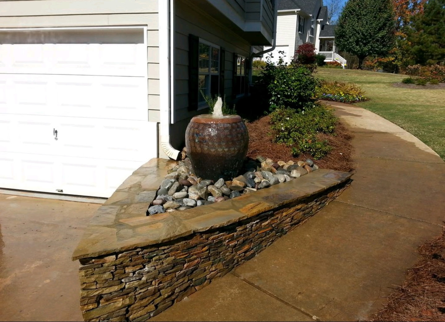 Brown ceramic urn fountain on a stacked-stone wall