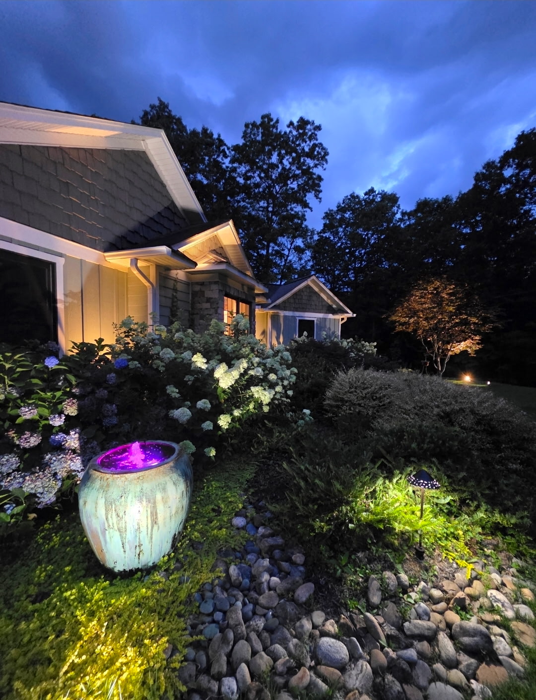 Teal urn fountain glowing with purple light at night