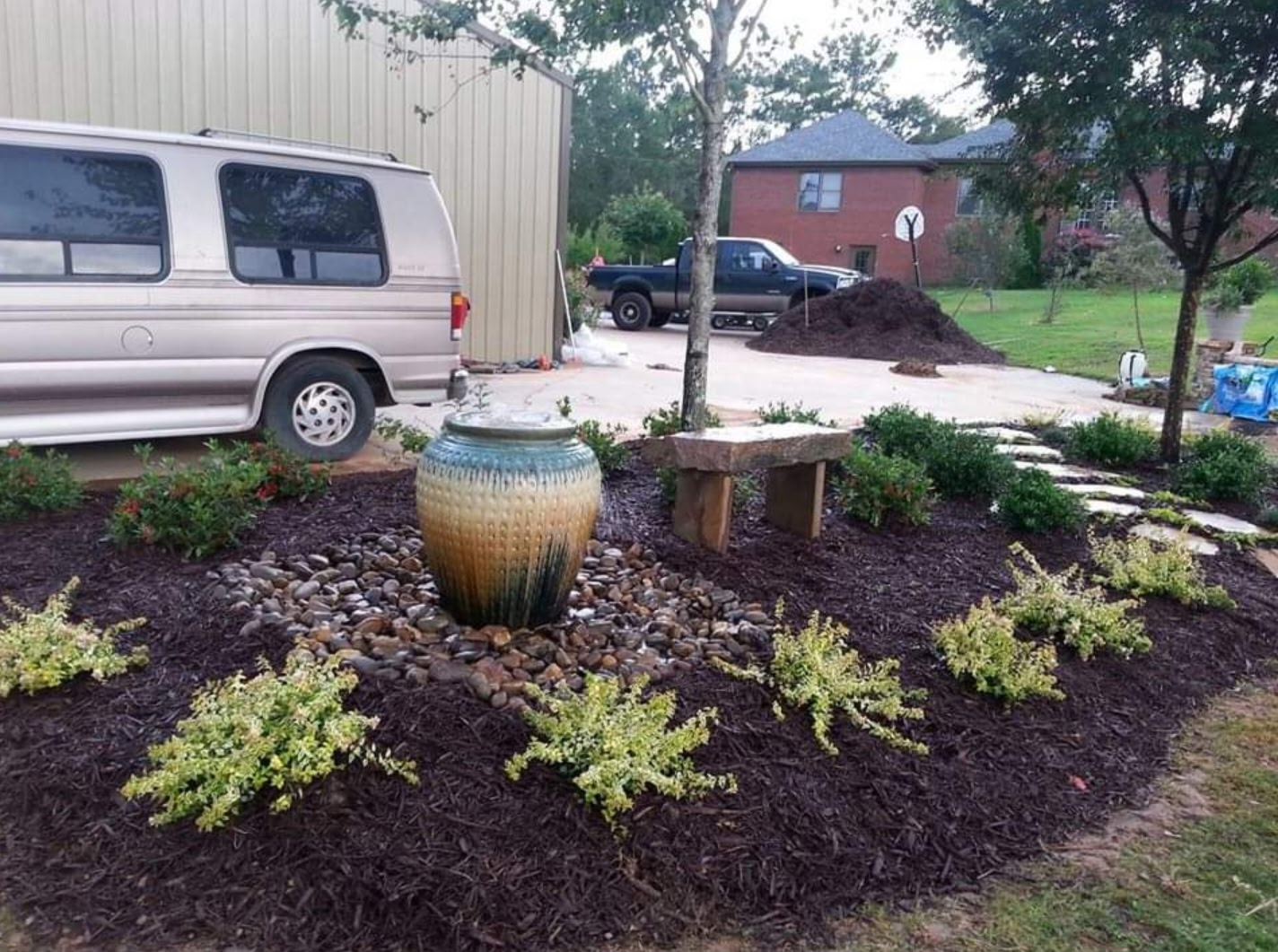 Glazed teal and tan urn fountain with a stone bench